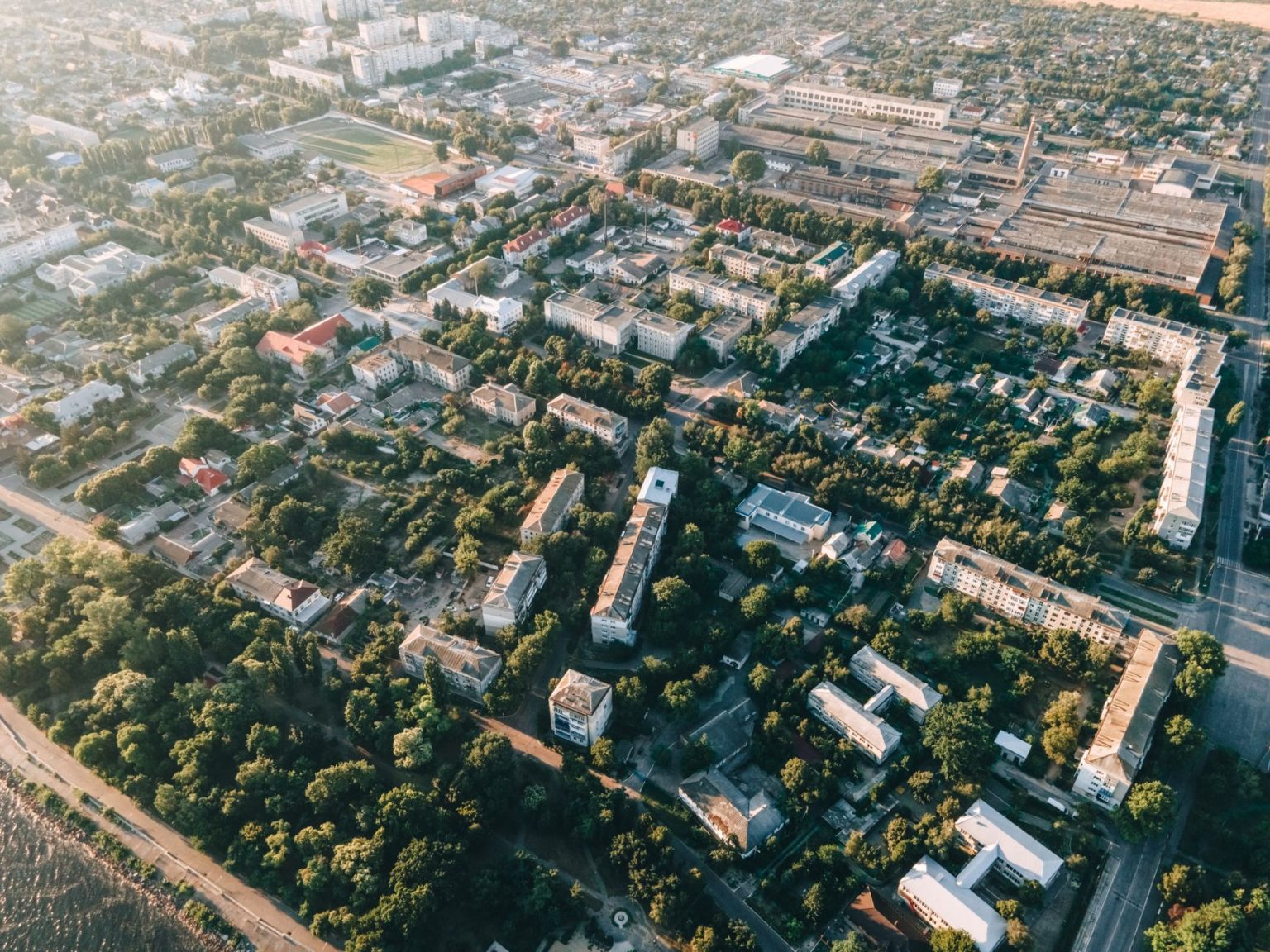Vista aérea de uma área urbana com casas, ruas e áreas verdes.