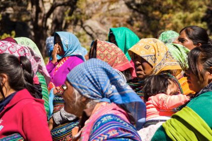 Grupo de mulheres indígenas usando trajes tradicionais durante uma reunião comunitária
