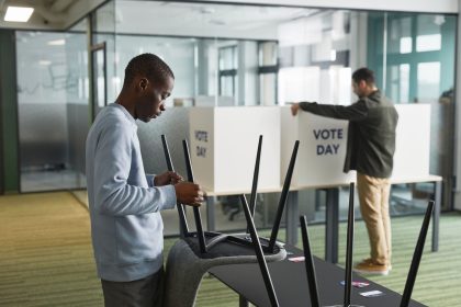 Pessoas preparam estruturas e equipamentos eleitorais em um ambiente interno.