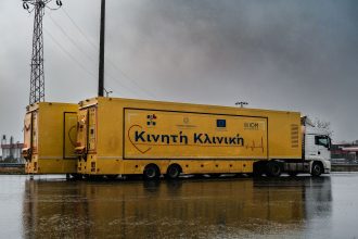 Carreta amarela de atendimento médico estacionada ao ar livre em um dia chuvoso.
