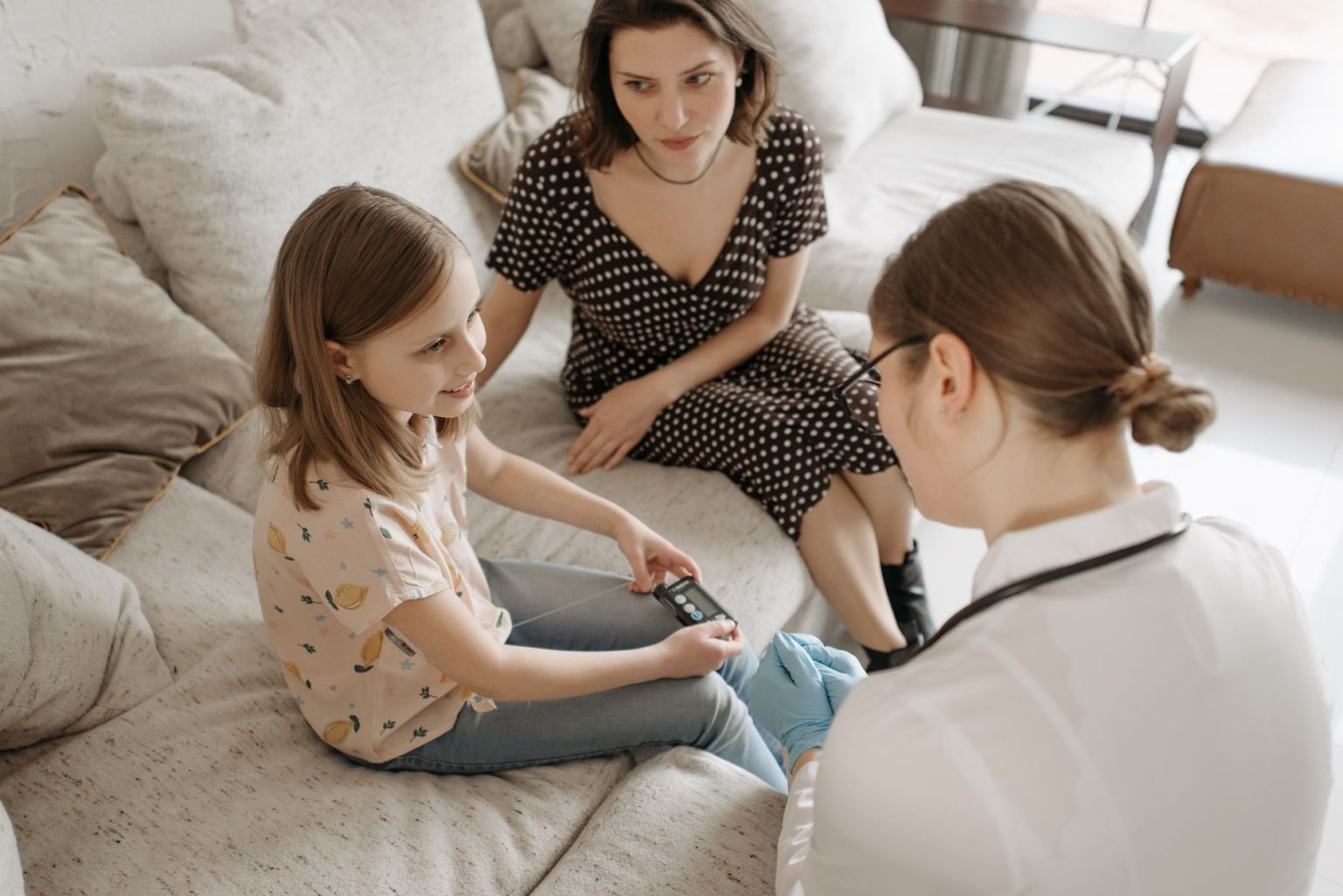 Profissional de saúde auxilia uma menina durante um atendimento para acompanhamento do diabetes em casa.