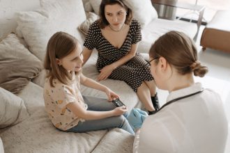 Profissional de saúde auxilia uma menina durante um atendimento para acompanhamento do diabetes em casa.