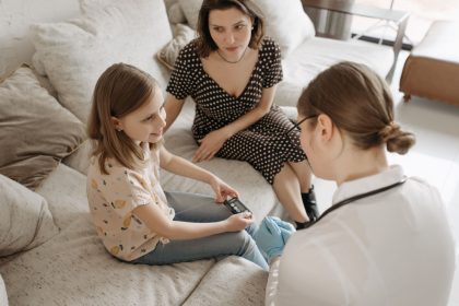 Profissional de saúde auxilia uma menina durante um atendimento para acompanhamento do diabetes em casa.