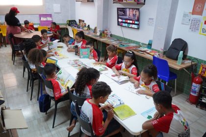 Crianças participam de uma atividade de leitura em uma biblioteca comunitária.