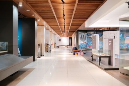 Corredor amplo e iluminado de uma exposição de design moderno, com ambientes e peças expostas.