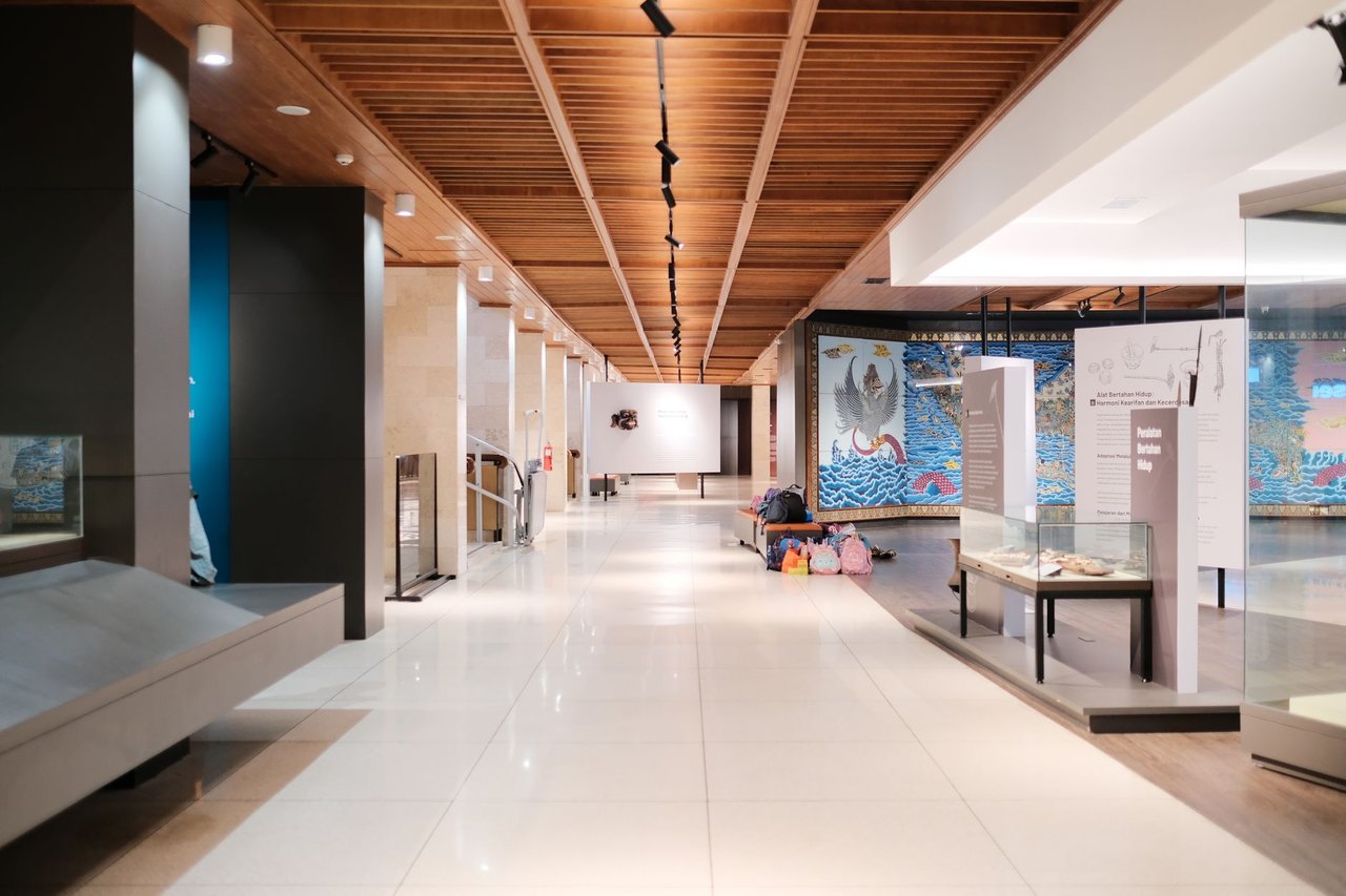 Corredor amplo e iluminado de uma exposição de design moderno, com ambientes e peças expostas.