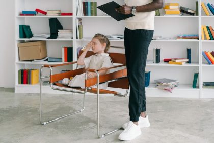 Criança participa de uma sessão de atendimento com uma profissional que segura uma prancheta, em uma sala reservada.